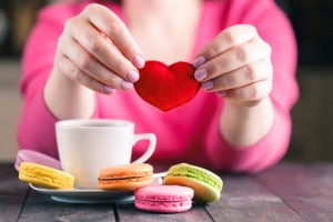 Woman drink coffee and holding in hands soft heart shape